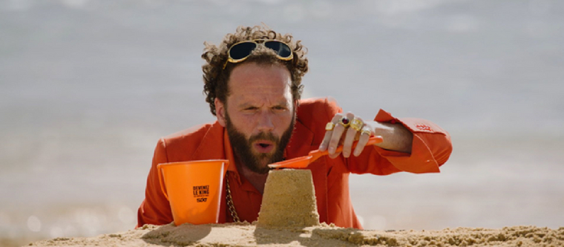 un homme qui fait un château de sable à la plage