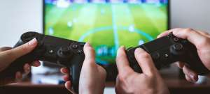 Deux manettes de console devant un jeu vidéo de football