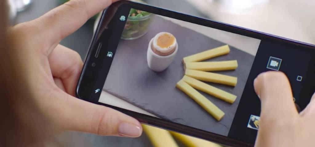 Un smartphone qui prend la photo d'un oeuf à la coque avec des lamelles de comté