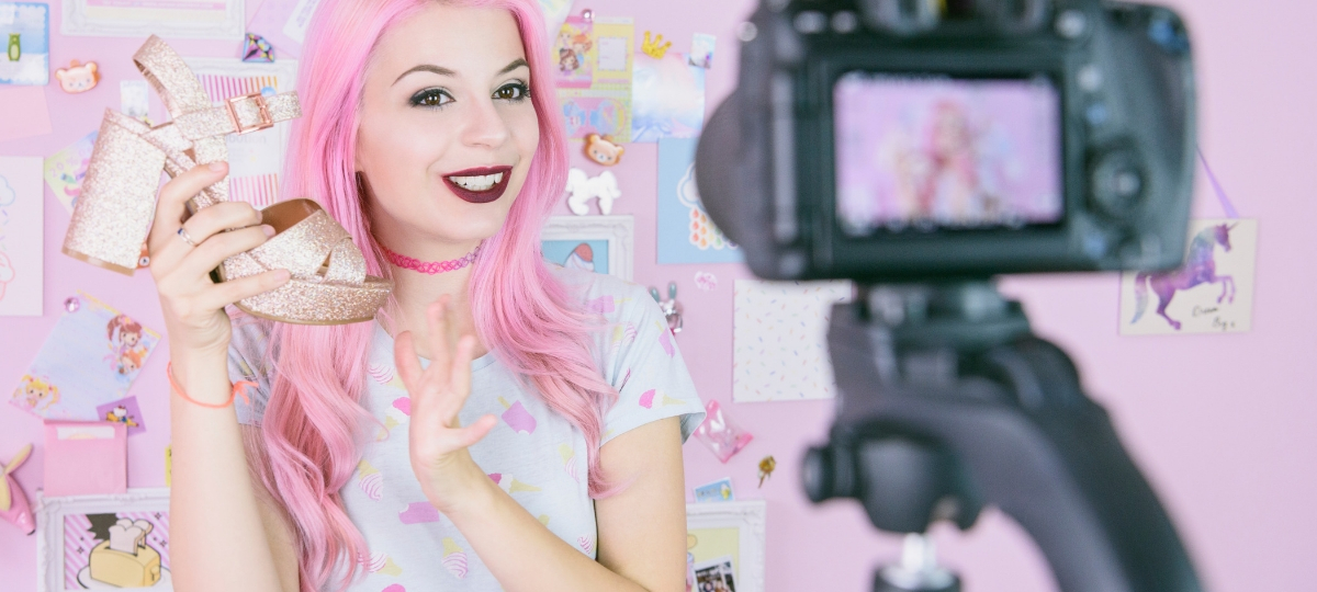 Comment faire une bonne campagne de content marketing avec des influenceurs ? Une influenceuse avec des cheveux roses qui se filme une chaussure à la main