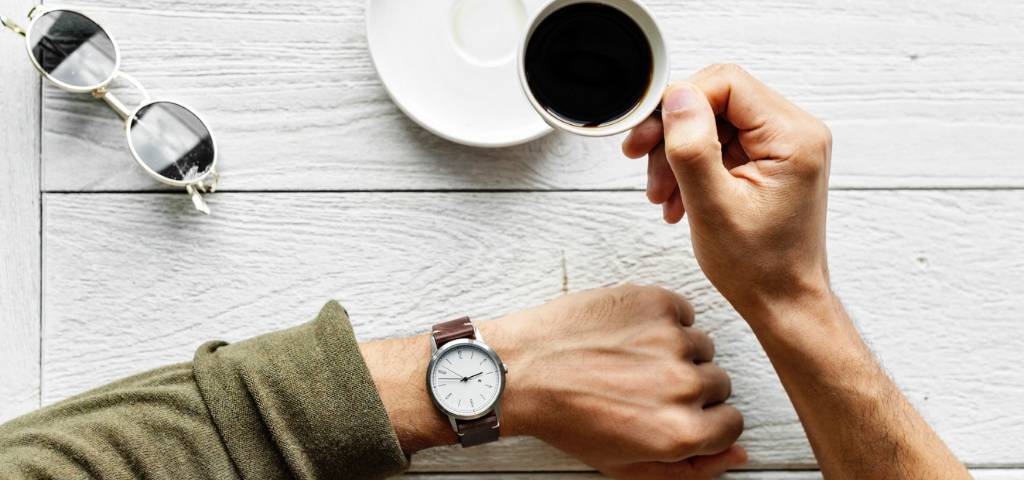 Une main d'homme avec une montre et un café