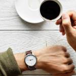 Une main d'homme avec une montre et un café