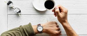 Une main d'homme avec une montre et un café