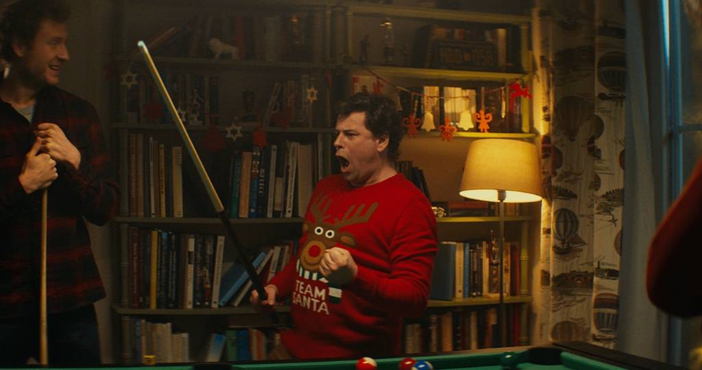 Un homme avec un pull de Noël qui fait du billard