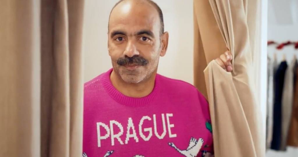 Un homme avec une moustache et un pull rose