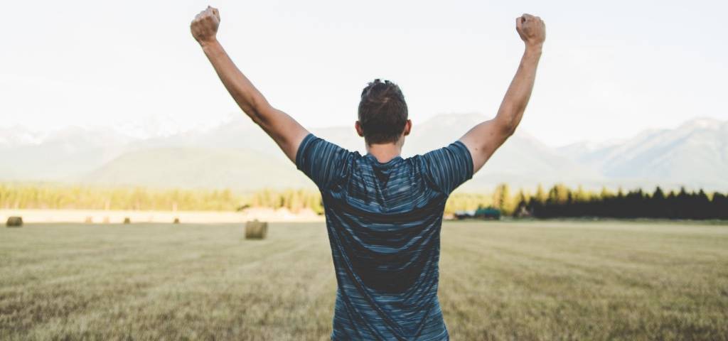 Un homme de dos qui lève les bras
