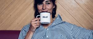 Une femme qui boit dans une tasse avec écrit Huel