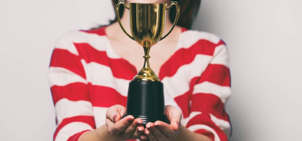 Une femme avec un t-shirt rayé qui tient un trophée