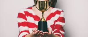 Une femme avec un t-shirt rayé qui tient un trophée