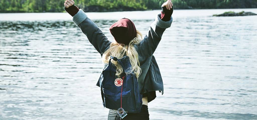 Une femme de dos qui lève les bras