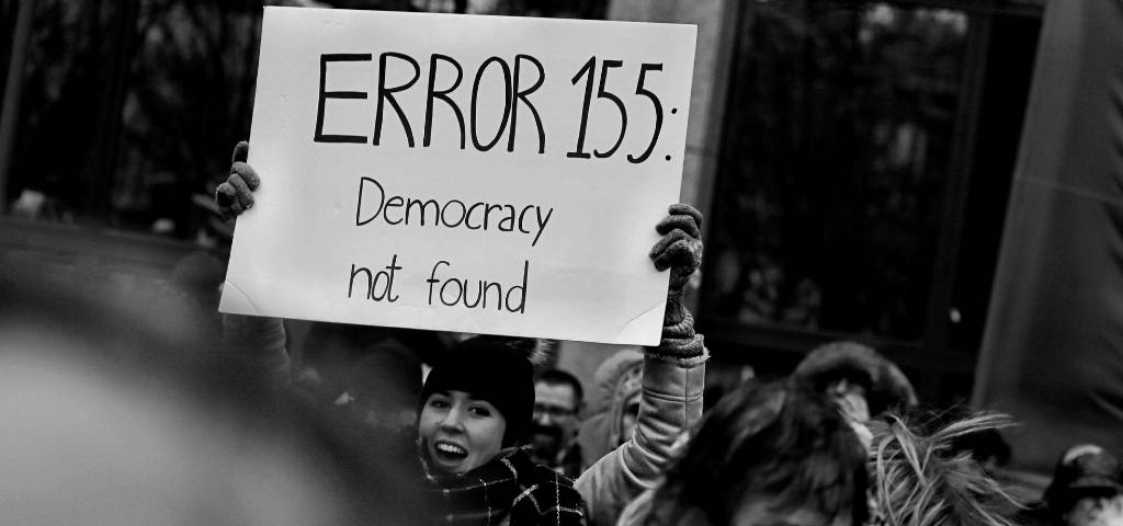 Une femme qui brandit une pancarte Error 155 Democracy not found