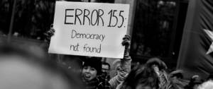 Une femme qui brandit une pancarte Error 155 Democracy not found