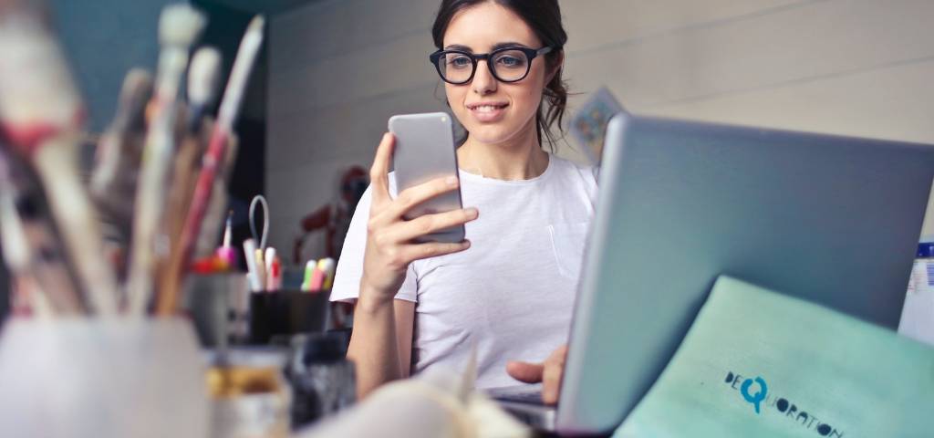 Une femme avec son smartphone devant son ordinateur