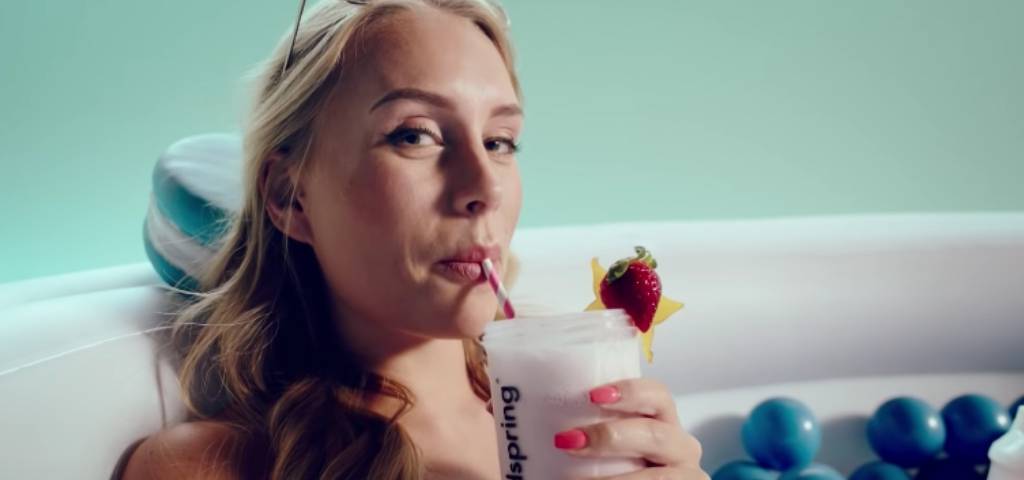 Une femme qui boit un smoothie dans sa baignoire