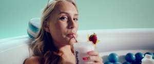 Une femme qui boit un smoothie dans sa baignoire