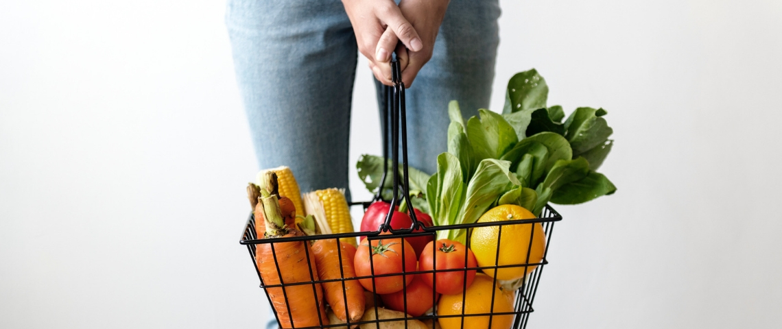 Leclerc ouvre un drive piéton à Paris Une personne qui tient un panier de supermarché rempli de fruits et légumes