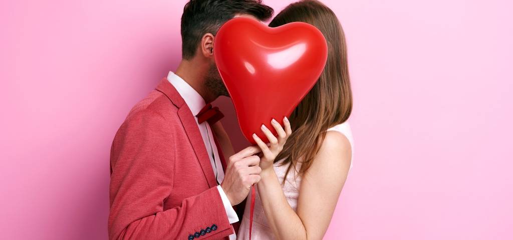 Un couple derrière un ballon rouge en forme de coeur