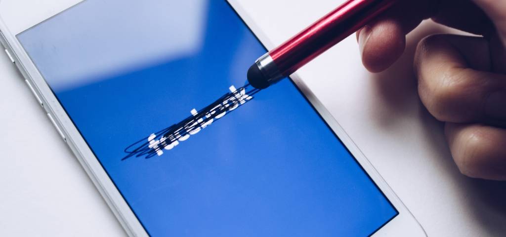 Un smartphone avec le logo Facebook rayé par un stylo