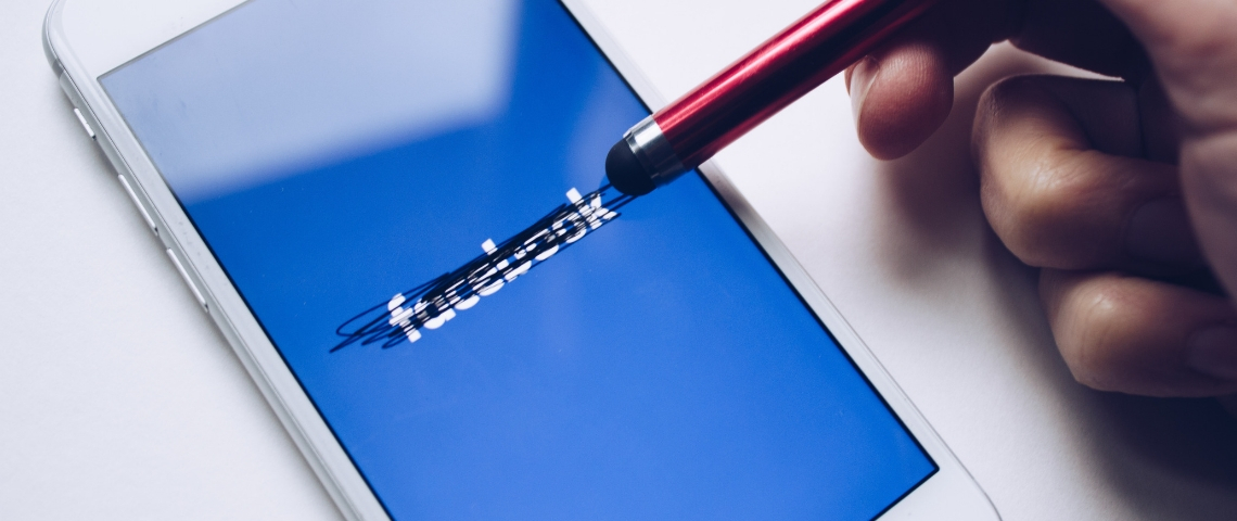 Facebook, le gangster du numérique Un smartphone avec le logo Facebook rayé par un stylo