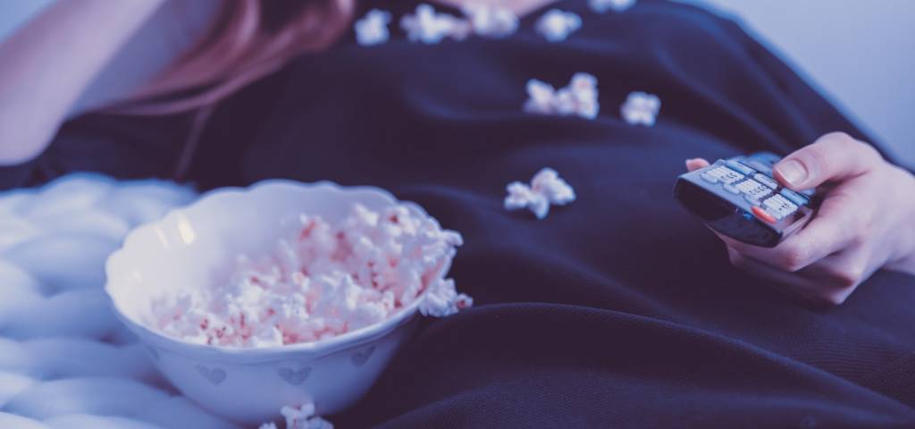 Une femme qui regarde la télé en mangeant du popcorn
