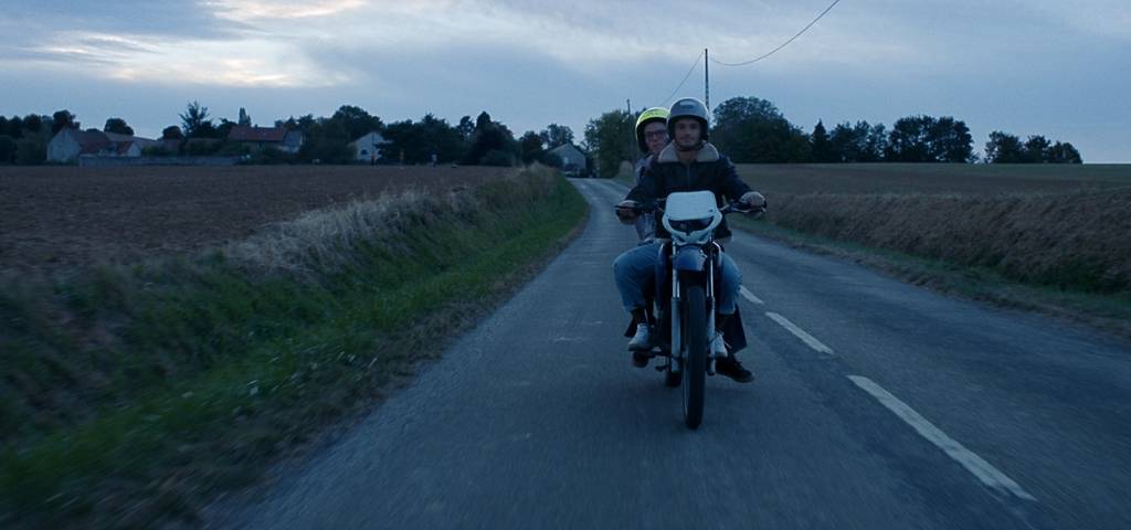 Deux hommes sur un scooter sur une route de campagne