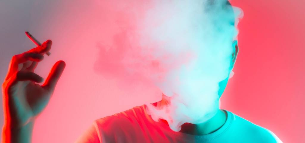 Un homme qui fume une cigarette avec la tête dans un nuage de fumée
