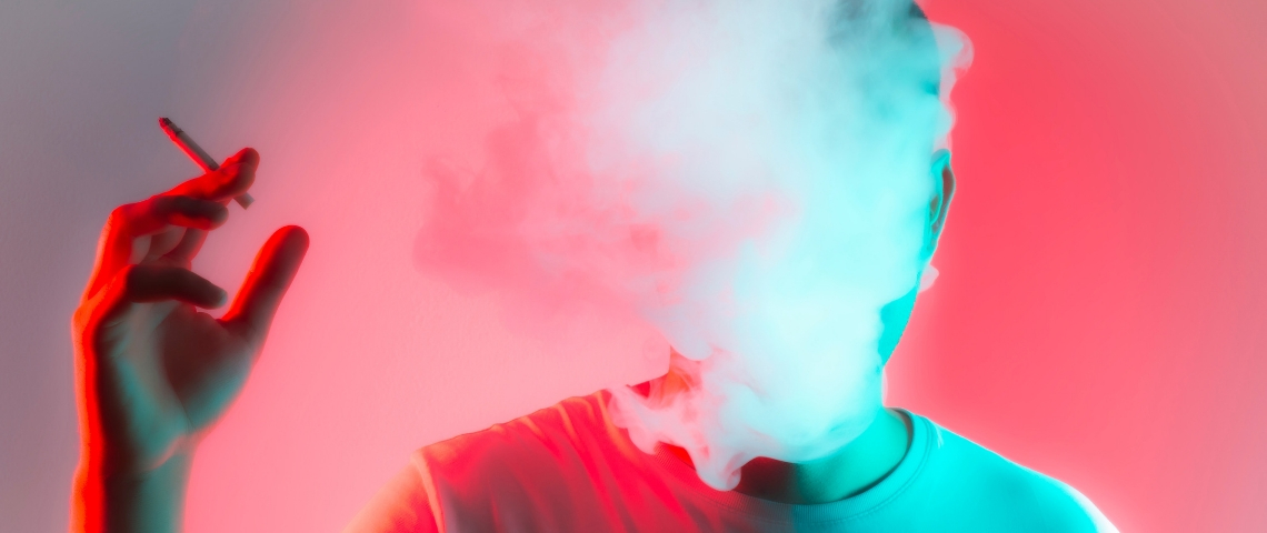 Un chatbot pour gérer son stress ou arrêter de fumer ? Un homme qui fume une cigarette avec la tête dans un nuage de fumée