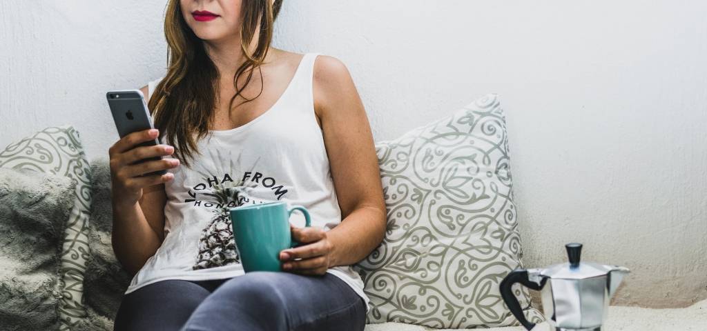 Une femme sur un canapé avec un smartphone à la main