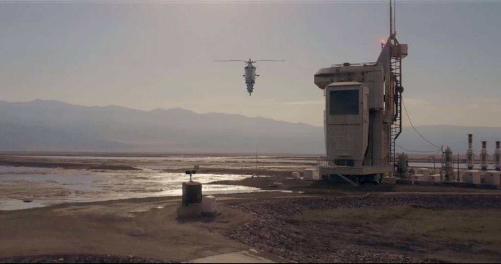Plan large d'un desert en présence d'un engin volant et d'une usine