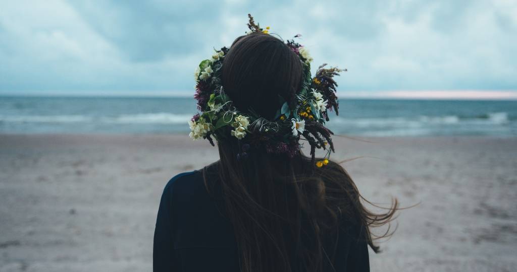 Les entreprises doivent-elles communiquer sur leurs actions RSE ?  Une femme brune de dos face à la mer avec une couronne de fleurs dans les cheveux