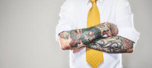 Un homme avec un cravate jaune et des tatouages sur les bras