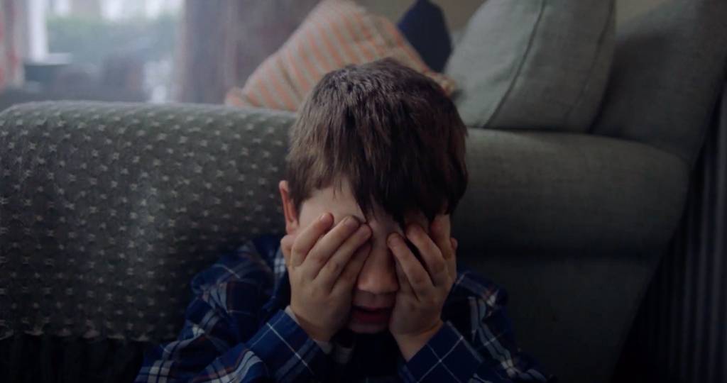 Un jeune garçon avec ses mains sur les yeux