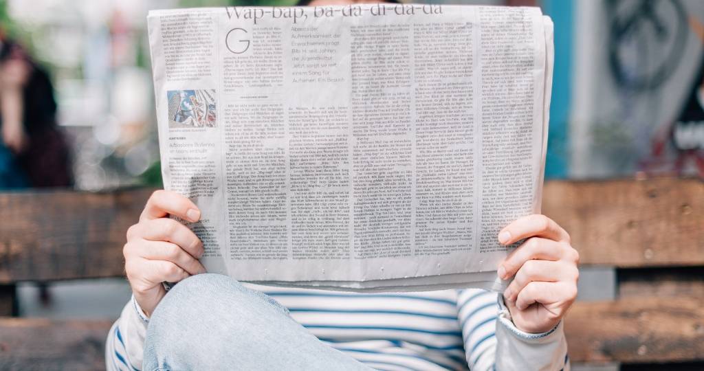 Homme sur un banc lisant un journal