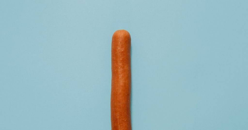 Une saucisse sur fond bleu pastell