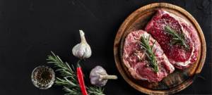 Deux morceaux de viande de boeuf placé sur une planche, sur une table en ardoise