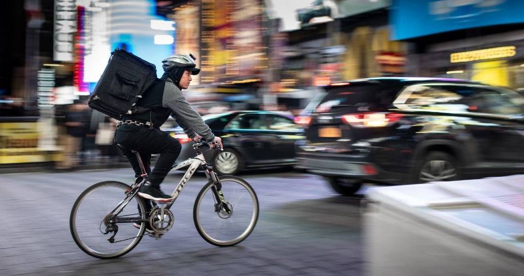 Un livreur en vélo, traverse un centre-ville