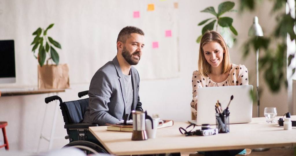 Une femme et un homme en fauteuil roulant discutent dans un bureau