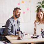 Une femme et un homme en fauteuil roulant discutent dans un bureau