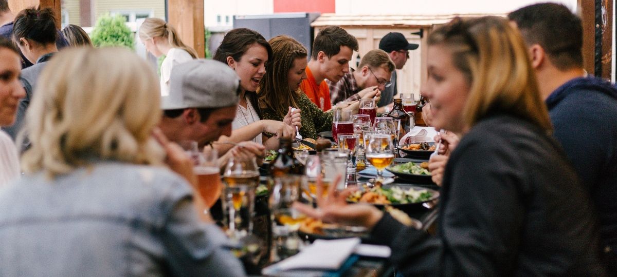 Et si vous demandiez à google de commander à votre place ? Un groupe d'amis dinent autour d'une table de restaurant fleurie et animée