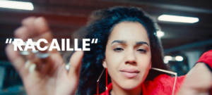 Une jeune fille porte une veste rouge. Il est inscrit à sa droite ''racaille''