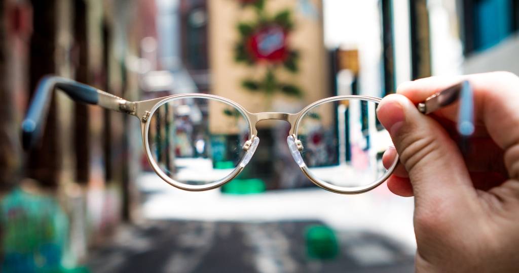 Une main tenant une paire de lunettes dans une rue
