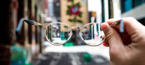 Une main tenant une paire de lunettes dans une rue