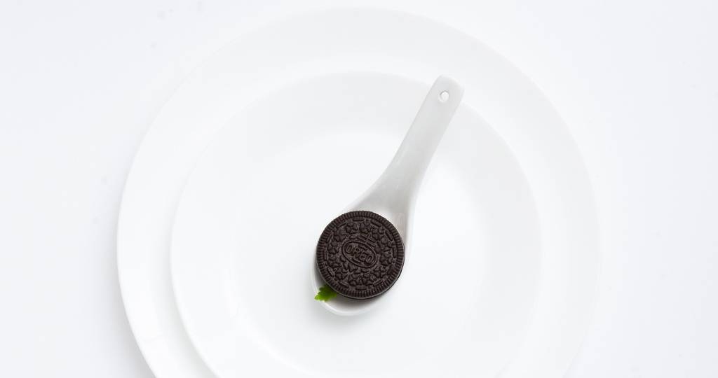 Biscuit Oreo placé dans une assiette blanche, sur fond blanc minimaliste