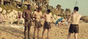 Trois hommes sur une plage, portent des maillots Pornhub