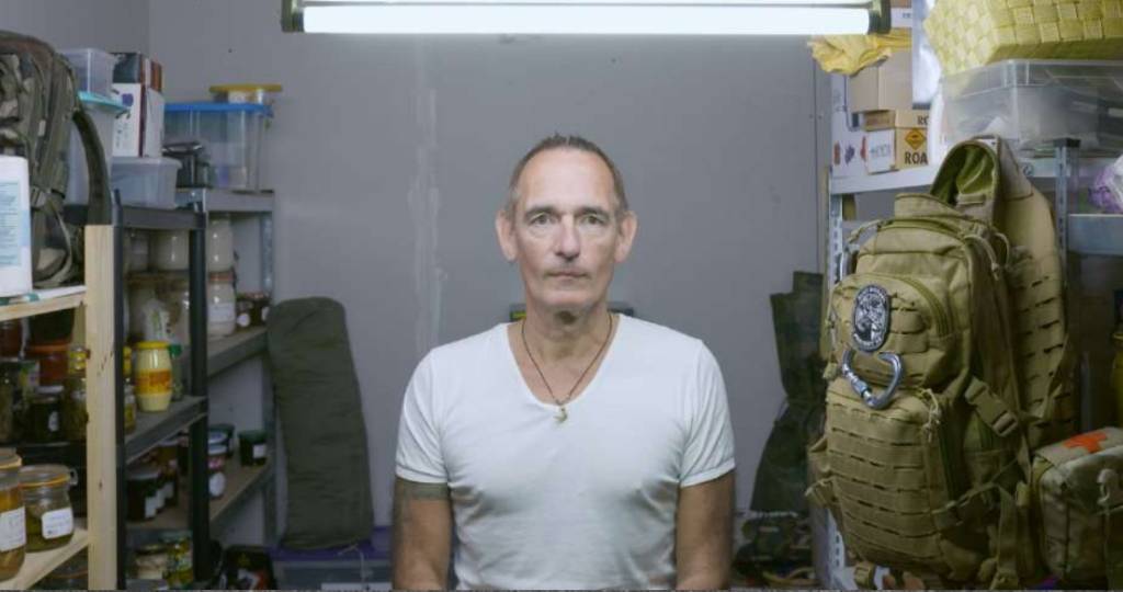 Un homme se tient de face dans son bunker de survie
