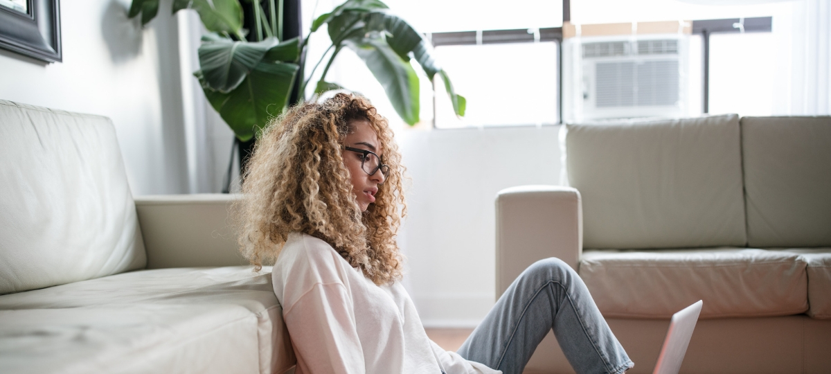 Voici les entreprises où les millennials rêvent de travailler une jeune femme travail sur son ordinateur. Elle est dans son salon assise contre son canapé