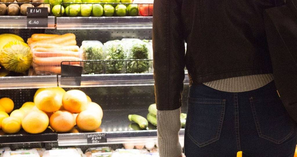 Une jeune femme se tient de dos devant un rayon de surperché