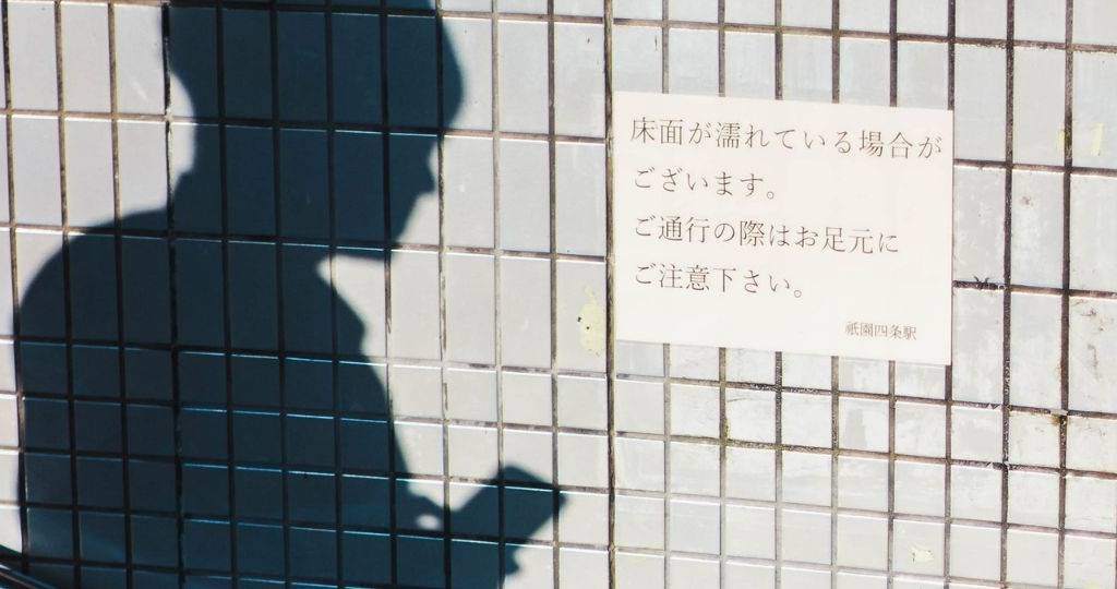Ombre d'un homme tenant son téléphone, sur le coté une affiche japonaise