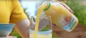 Gros plans sur une main versant du jus d'orange Tropicana