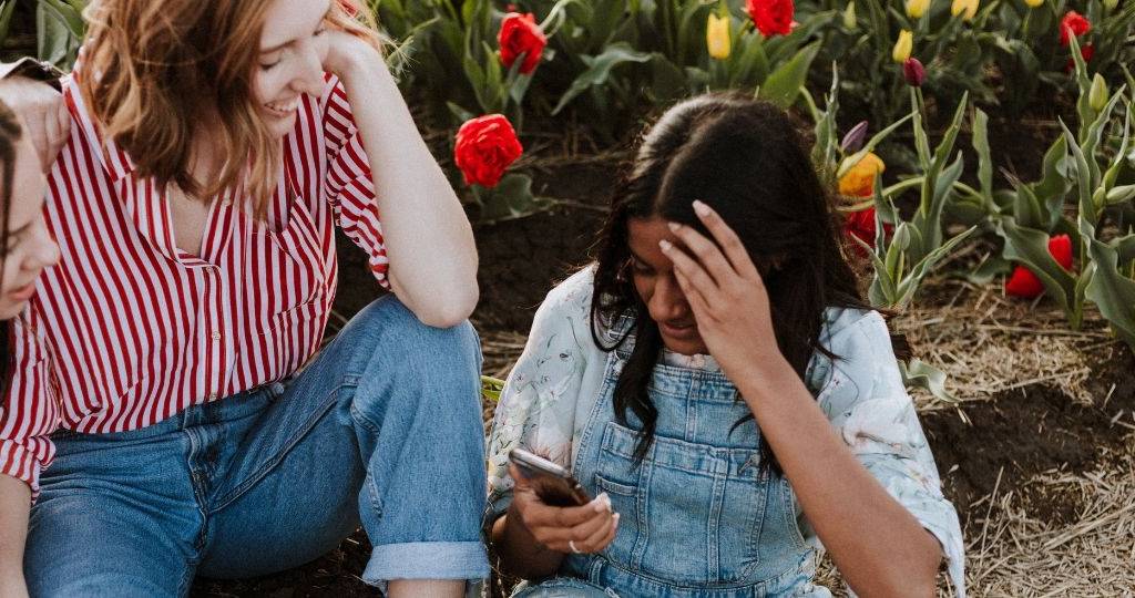 Trois jeunes femmes se prennent en photo sur un smartphone. Au milieu d'un champ de tulipes.